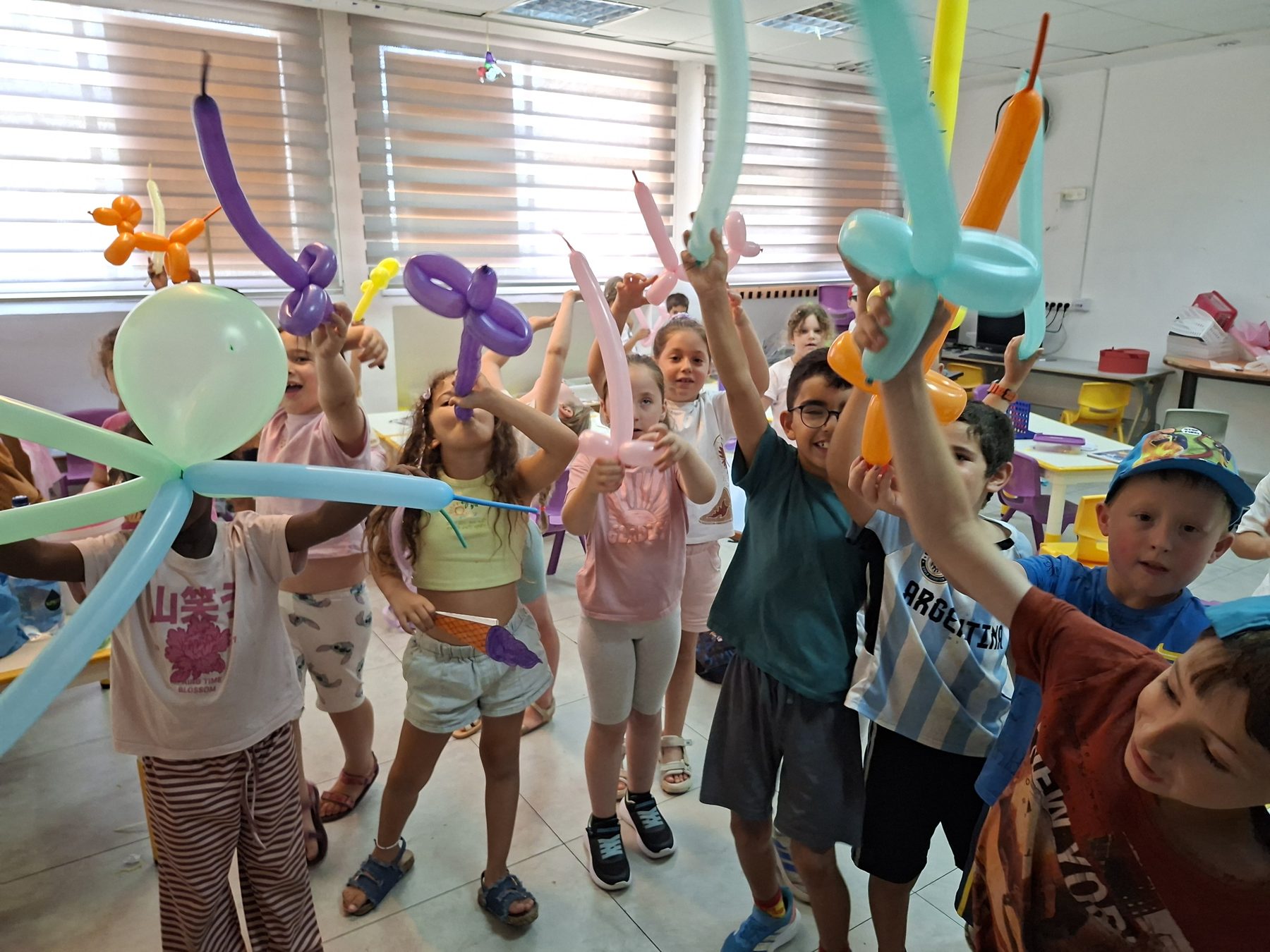 ילדים מרימים בלונים בצורות בשמחה בסוף הפעלה