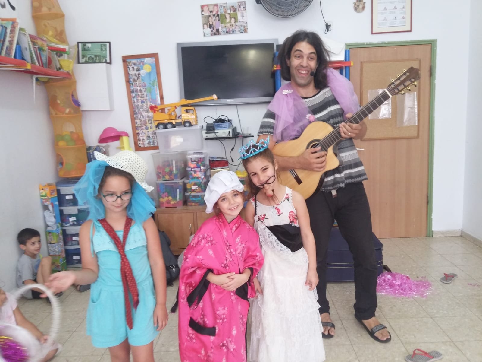 ינון בר שירה מנגן בגיטרה עם ילדות מחופשות בחוג מוסיקה-סיפור
