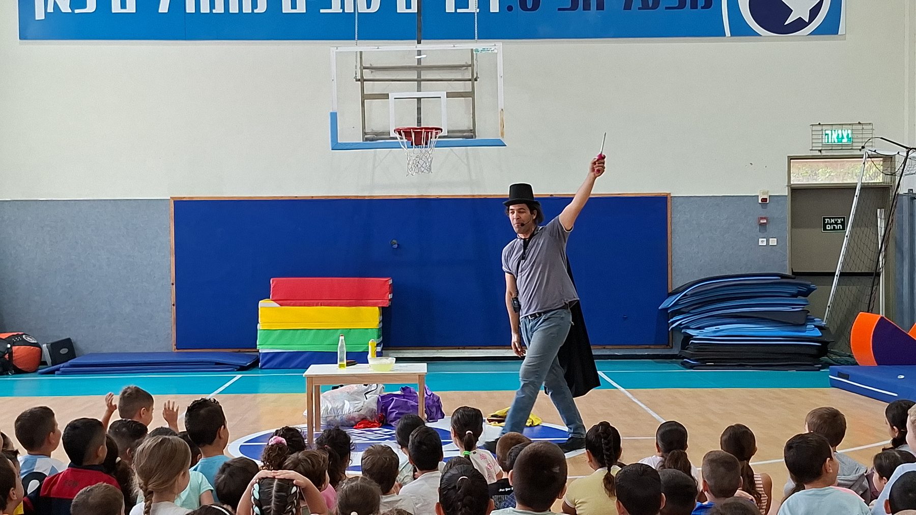 ינון בר שירה עם מגבעת קוסם מבצע קסם מול קהל ילדים